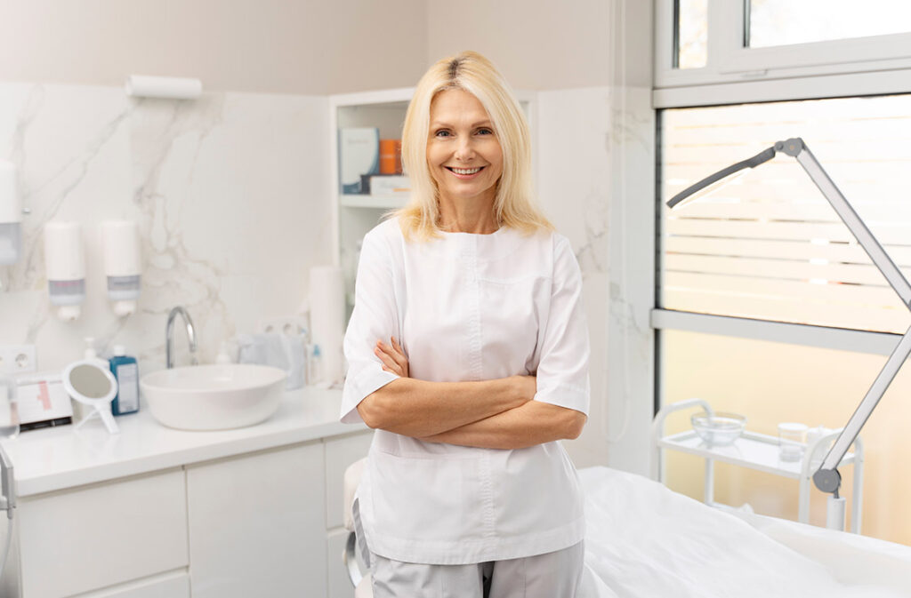 Older woman smiling in a light therapy treatment room for skin rejuvenation.