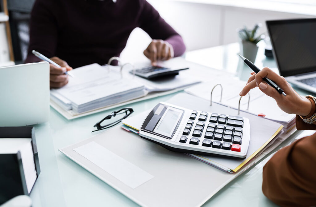 Two people discussing finances at a desk during tax season consultation.